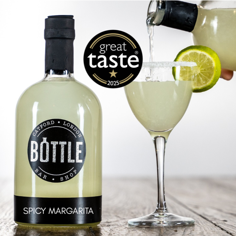 Bottle of Spicy Margarita being poured into a glass with a lime wedge, with 'Great Taste' award visible.